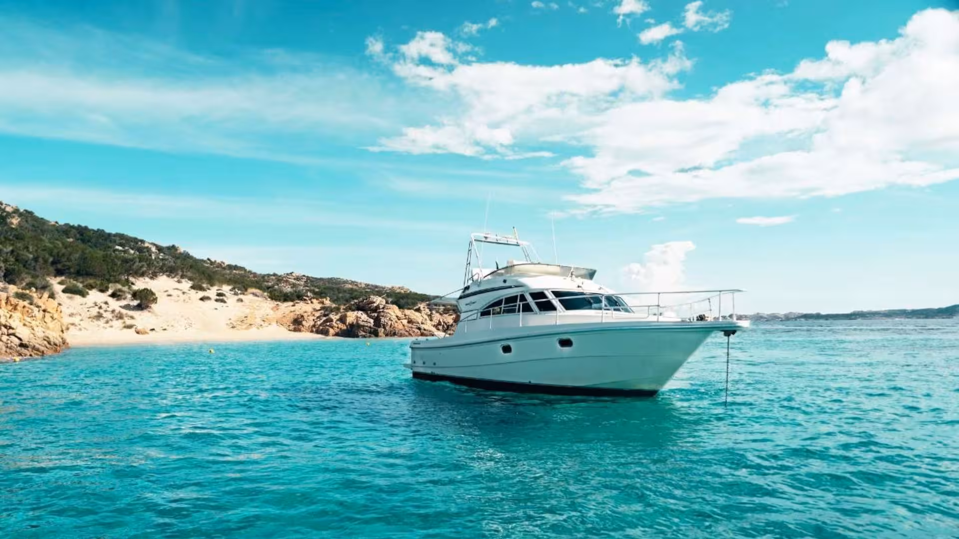 Luxury yacht anchored in the clear blue waters of La Maddalena with scenic coastal views, perfect for a mini yacht tour.