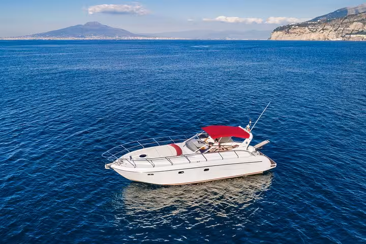 Elegant yacht cruising on clear blue waters with Mount Vesuvius in the backdrop, ideal for a Sorrento getaway.