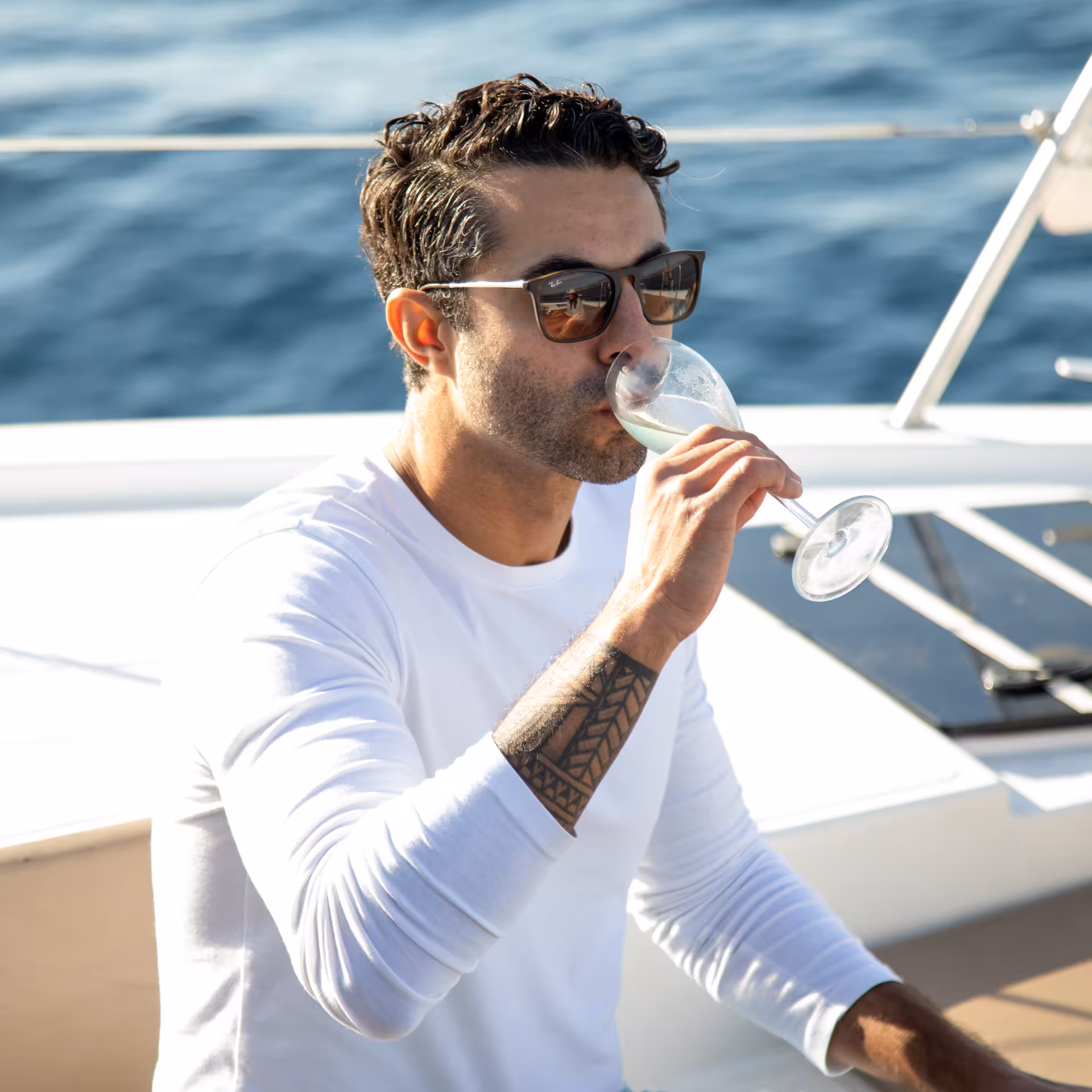 Guest sipping sparkling wine on a luxury yacht during Farewell at Sea sunset cruise with ocean views
