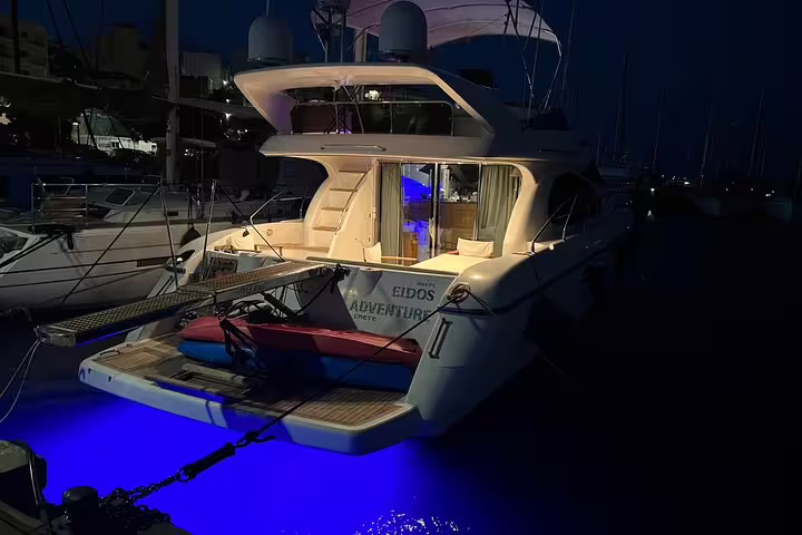 Luxury yacht illuminated at night in marina, perfect for wine tasting and gourmet dining under the stars.