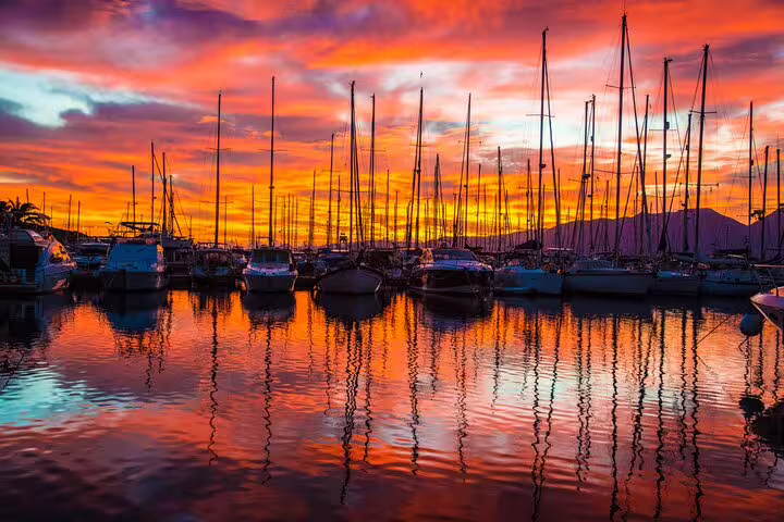 Vibrant marina sunset with yachts, offering a stunning backdrop for an evening of wine tasting and fine dining.
