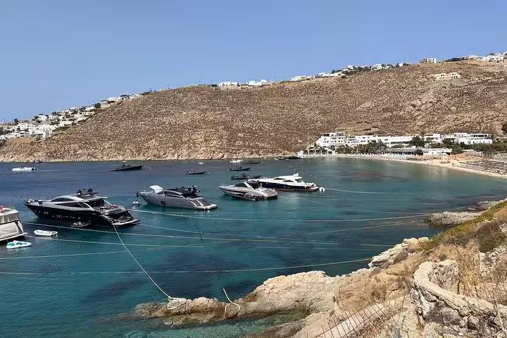 Luxury yachts anchored in a turquoise Mykonos bay, coastal photo stop on a private Mykonos top sights tour