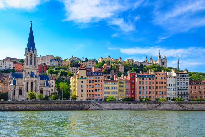 Colorful buildings along the Saône river with church spire and Fourvière hill in Lyon, France