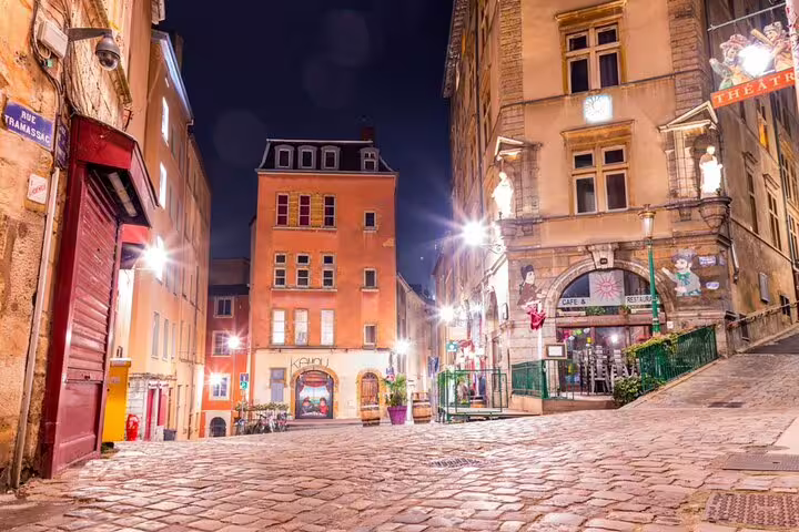 Cobblestone street in Old Lyon at night with glowing lights and historic buildings