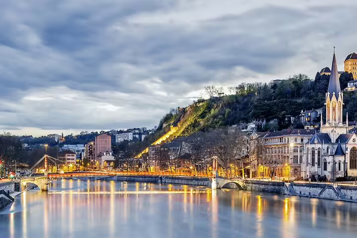 Lyon city skyline at dusk with illuminated bridge over the Saône River and Gothic church