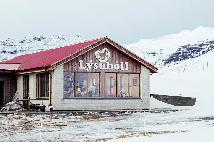 Lýsuhóll guesthouse building with red roof surrounded by snow-covered mountains in Snaefellsnes, Iceland