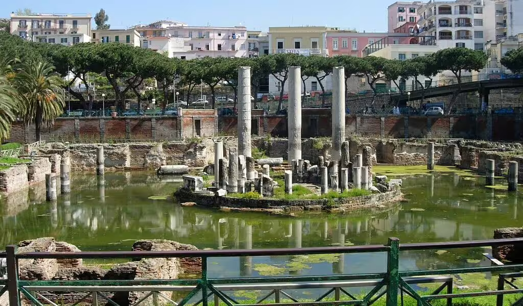 Roman ruins of the submerged Macellum of Pozzuoli with marble columns rising from a green pool on a Naples day trip