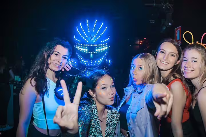 Group of friends enjoying a vibrant night out in Madrid, featuring LED-lit performer at Mad Party Crew's Pub Crawl experience.