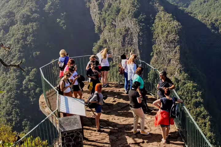 Tourists enjoy stunning cliffside views on a Full Day Private 4x4 Adventure in Madeira, surrounded by lush greenery and rugged terrain.