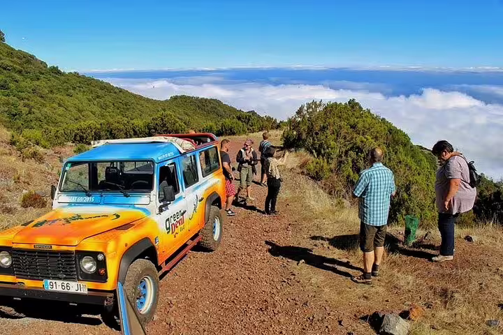 Jeep safari adventure on Madeira's Cabo Girão, with tourists exploring rugged landscapes and scenic views above the clouds.