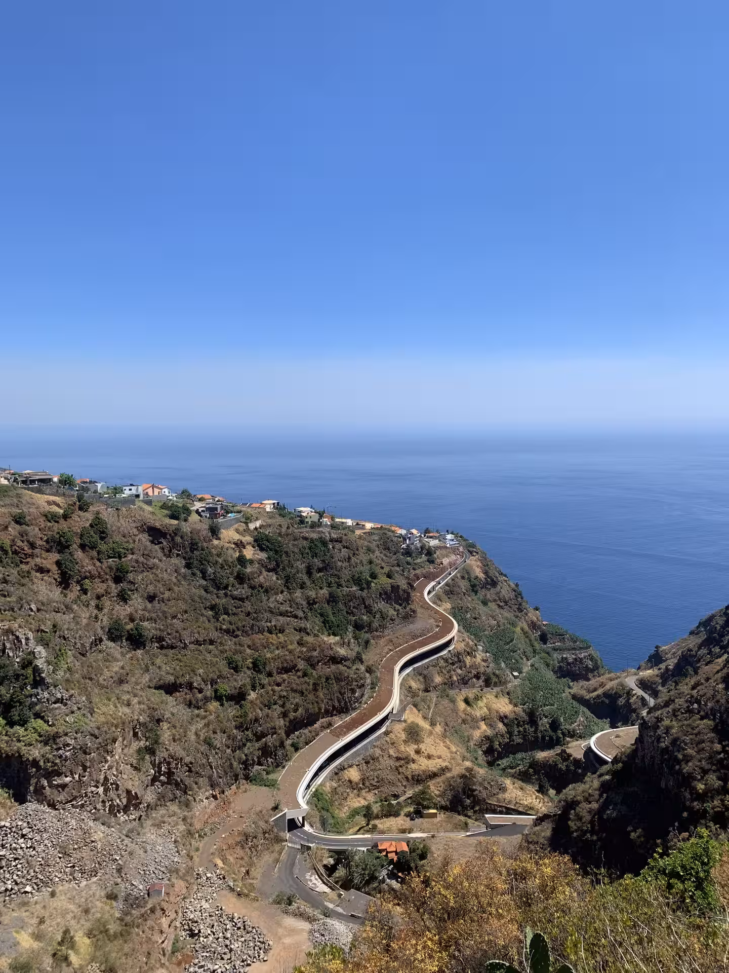Scenic winding coastal road snaking along Madeira's dramatic mountain cliffs overlooking the Atlantic on a private tour