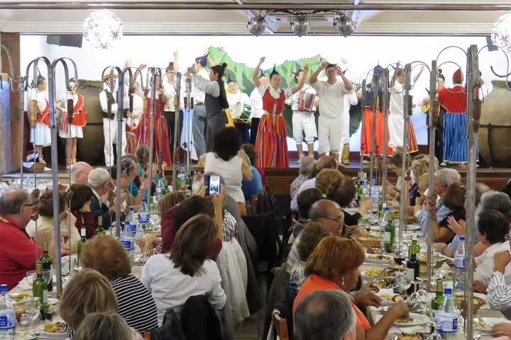 Lively Madeira dining experience with traditional folk dancers performing for a captivated audience at a banquet.