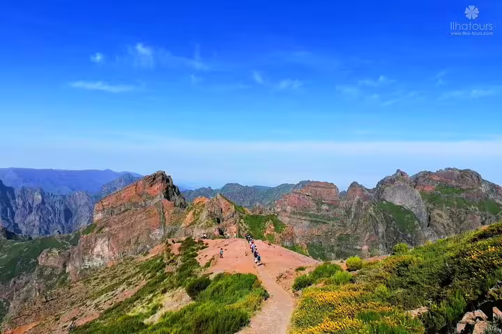 Hikers explore the stunning peaks of Madeira's eastern mountains under a clear blue sky, perfect for adventure tourism.