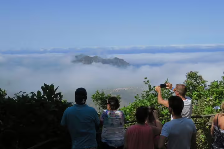 Tourists capturing the breathtaking view of Madeira's east peaks shrouded in mist, perfect for an unforgettable Santana excursion.