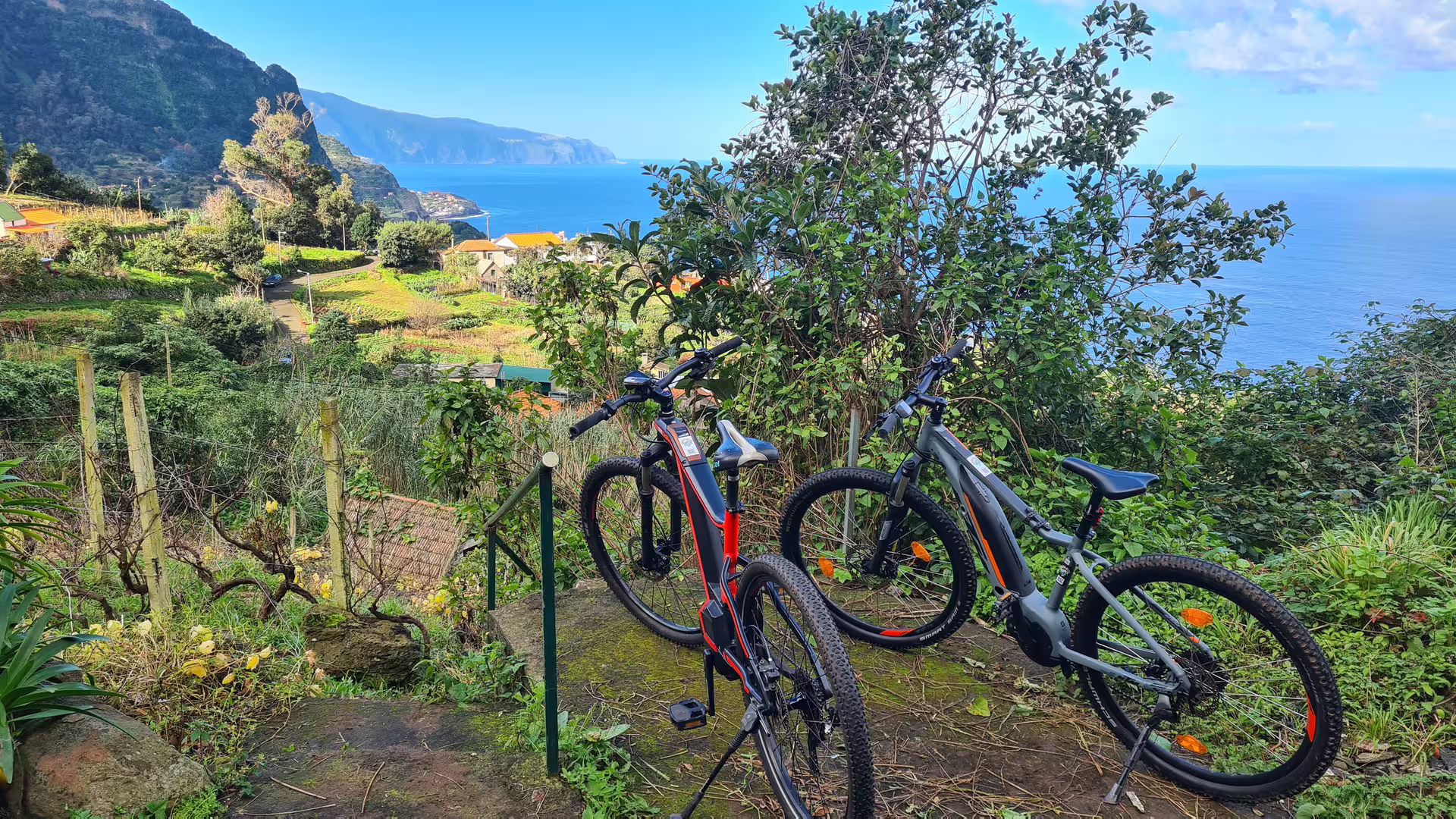 E-bikes parked with scenic views of Madeira's lush north coast and ocean, perfect for a guided cycling adventure.
