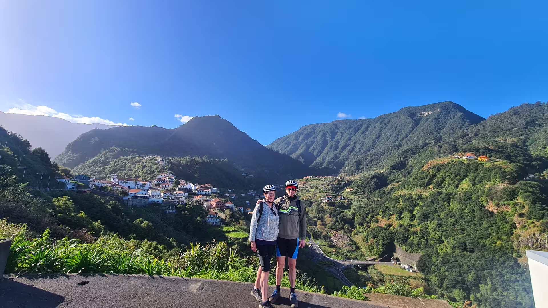 Two cyclists enjoy stunning mountain views on a guided e-bike tour along Madeira's scenic north coast.