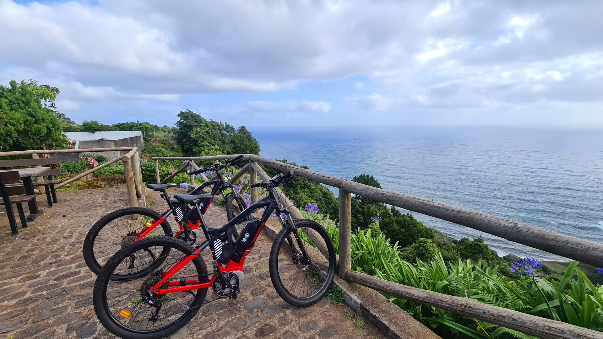 E-bikes parked on a scenic overlook along Madeira's stunning north coast, offering panoramic ocean views and lush greenery.
