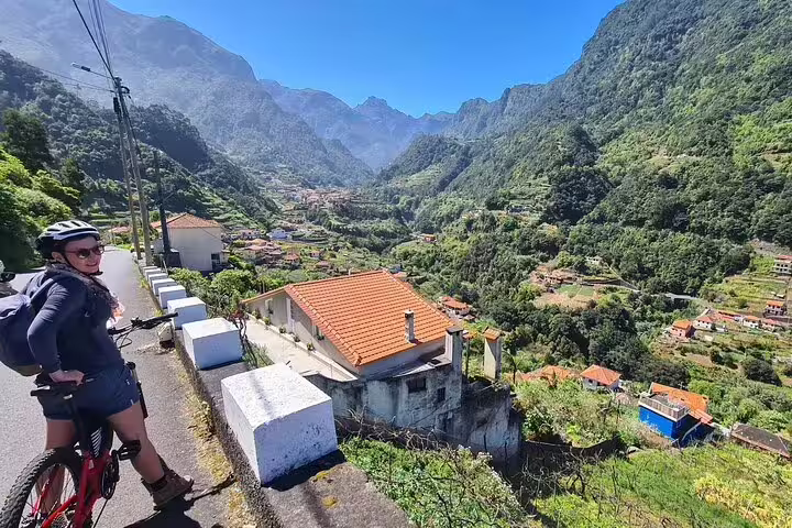 Cyclist enjoying a guided e-bike tour on Madeira's scenic north coast, surrounded by lush valleys and picturesque villages.
