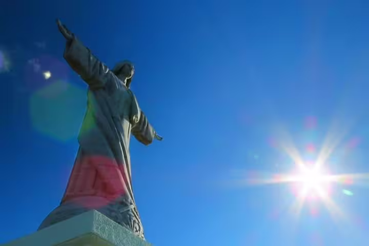 Statue silhouetted against a clear blue sky with a "Clean & Safe" badge, symbolizing safety on the Madeira highlights tour.