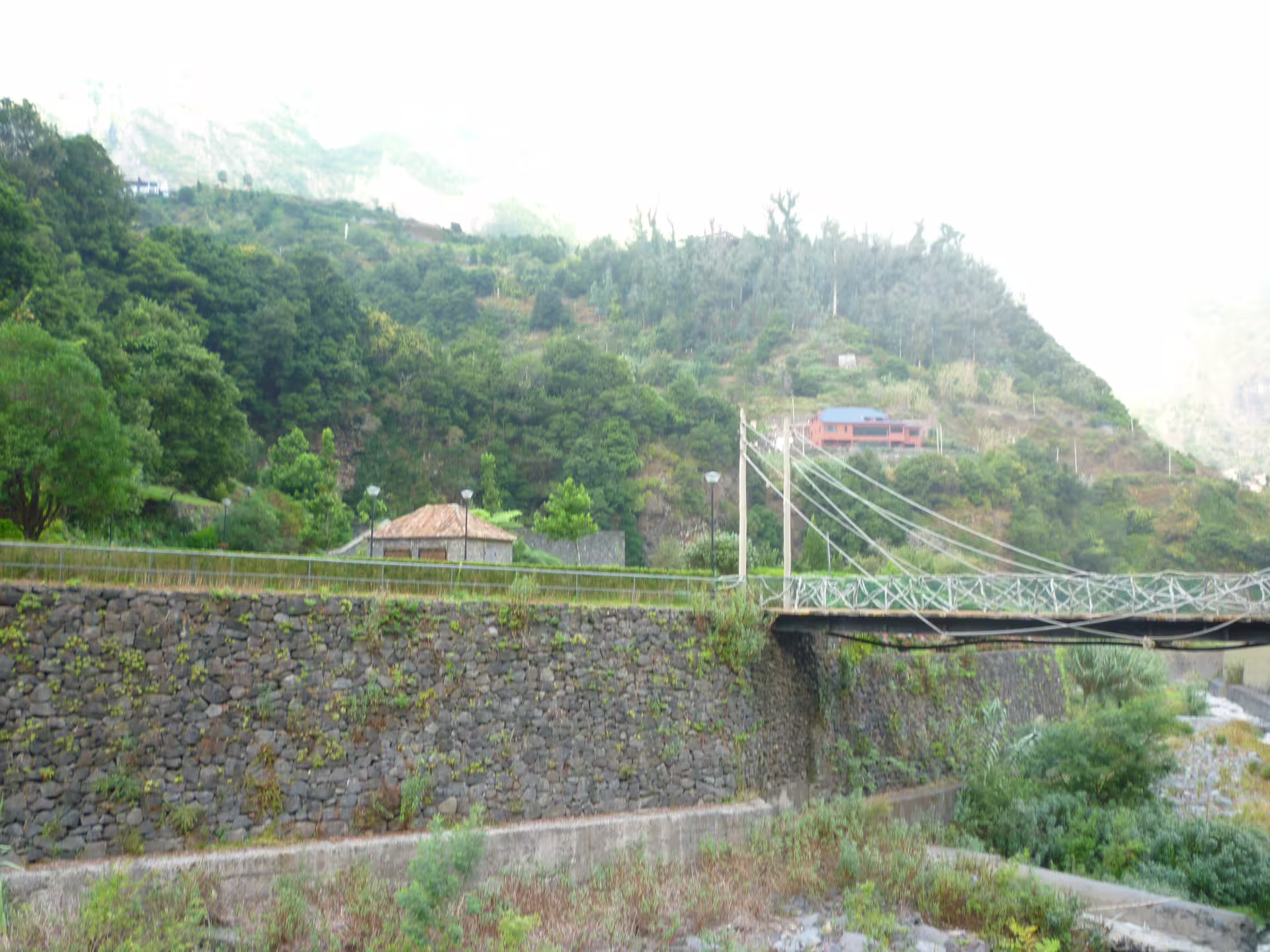 Lush green hills and a rustic bridge in Madeira's scenic countryside, ideal for exploration on the Around the Island Tour.