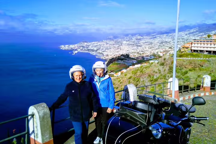 Couple enjoys breathtaking Madeira coast view during a scenic sidecar tour, ideal for adventurous exploration and sightseeing.
