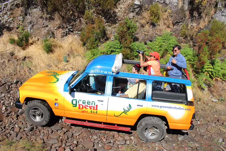 Tourists enjoying a scenic Madeira Peaks adventure in an open 4x4 vehicle by Green Devil Safari, exploring rugged landscapes.