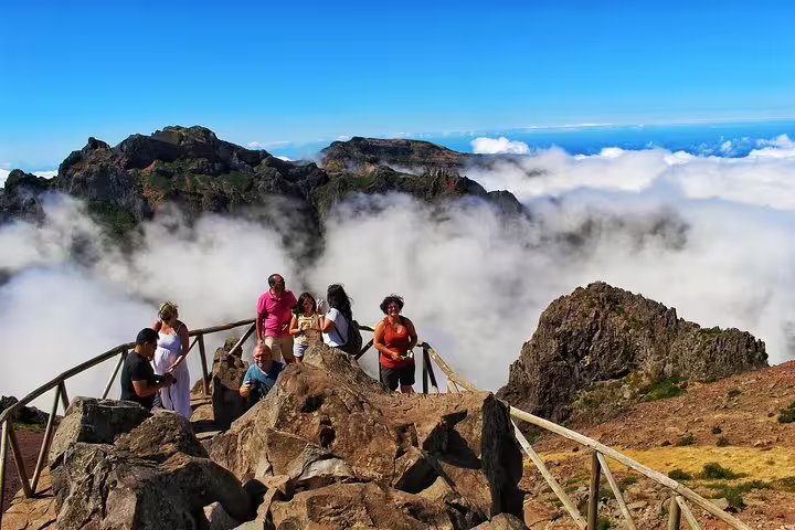 Tourists enjoying breathtaking views above the clouds from Madeira Peaks during an adventurous open 4X4 full-day tour.