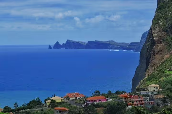 Scenic view of Madeira's coastline with vibrant houses and rugged cliffs, featured on the Madeira Peaks 4X4 Full-Day Tour.