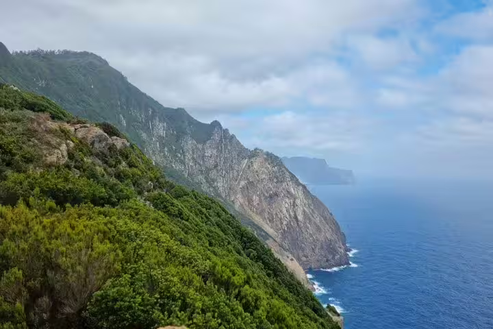 Scenic coastal view of Madeira's lush cliffs and azure Atlantic Ocean along the Porto da Cruz to Machico hiking trail.