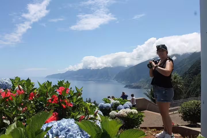 Tourist enjoys breathtaking ocean views and colorful flowers on Madeira's Enchanted Terraces with open-top jeep tour.
