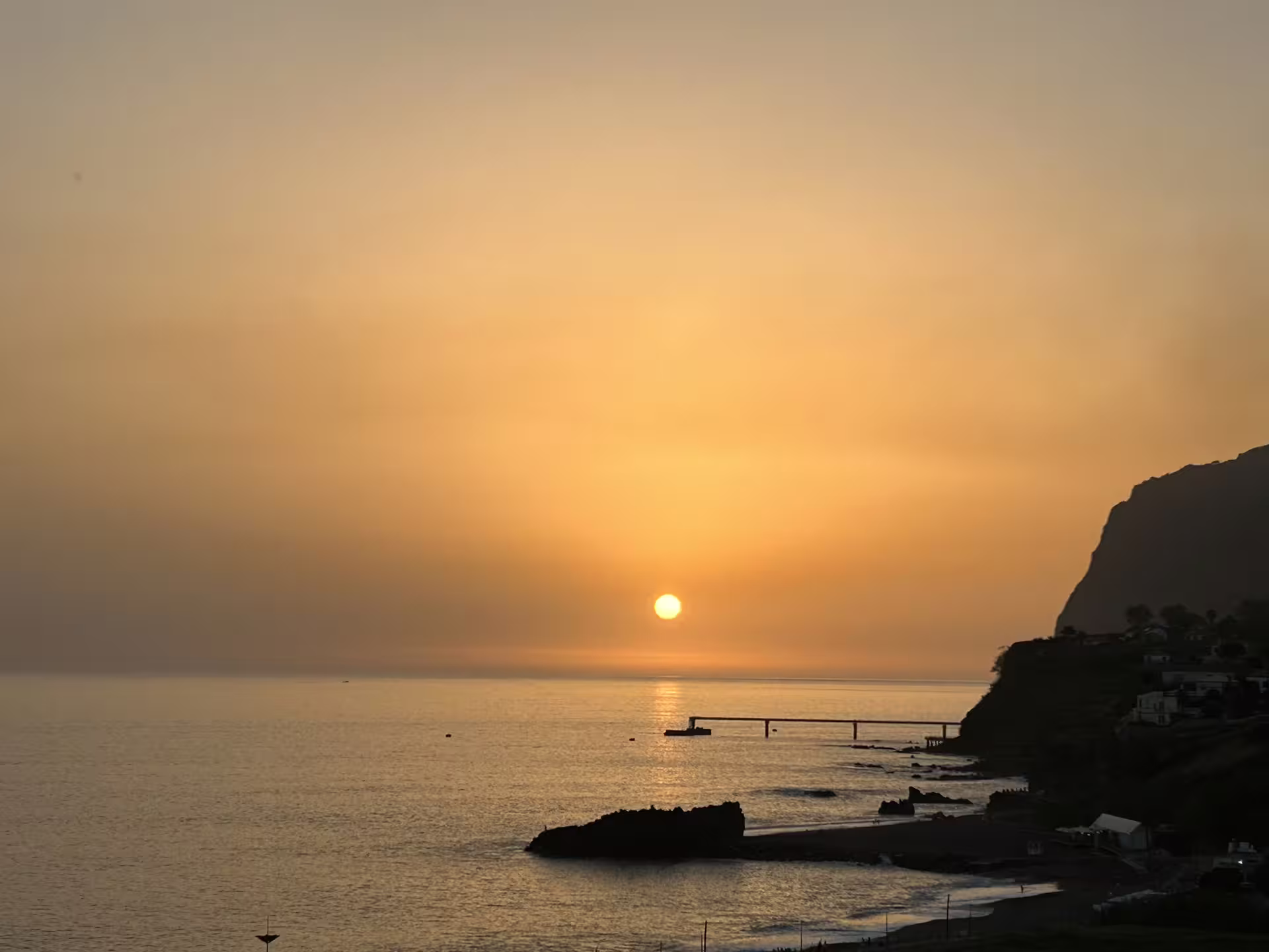 Sunset over the ocean near Madeira's cliffs, offering a serene view on a private, comfortable island tour.