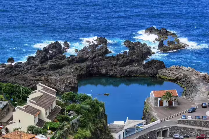 Scenic view of Madeira's rocky coastline with natural pools and charming coastal village, ideal for a magical shore excursion.