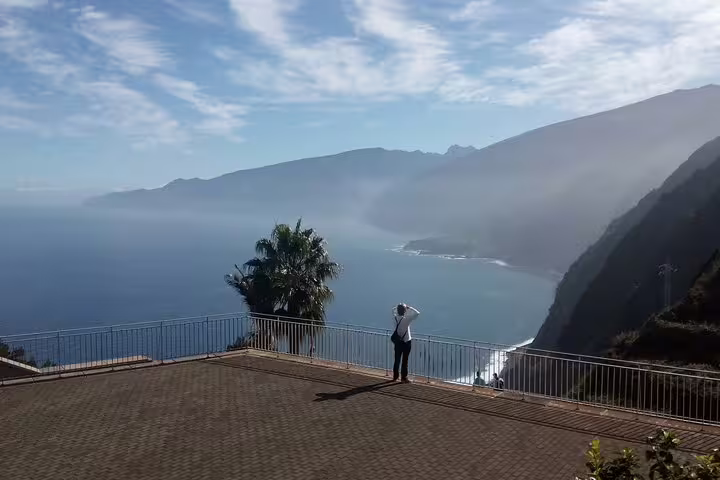 Scenic ocean view from a Madeira cliffside, with a person admiring the expansive Atlantic and rugged coastline.