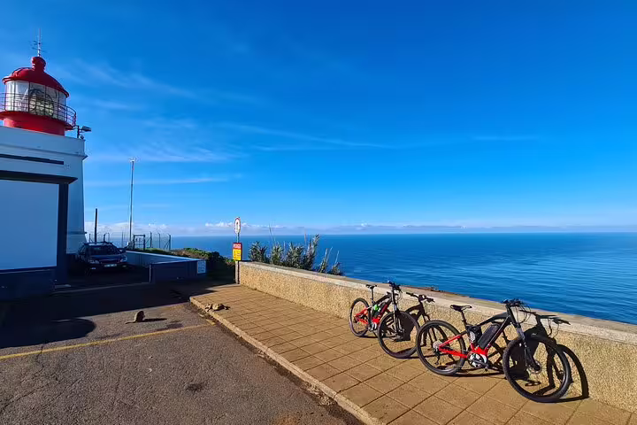 Scenic bike tour stop at Madeira's west coast lighthouse with ocean views, perfect for cycling enthusiasts exploring Portugal.