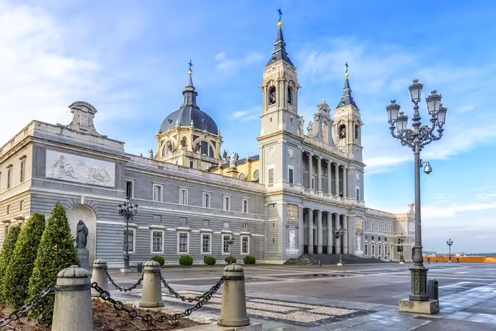 Almudena Cathedral and plaza in Madrid, Spain, with ornate lamp posts and blue sky