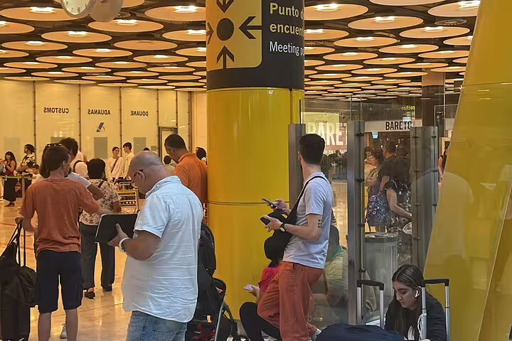 Madrid Barajas Airport meeting point area with waiting passengers, private transfer pickup to Madrid city center