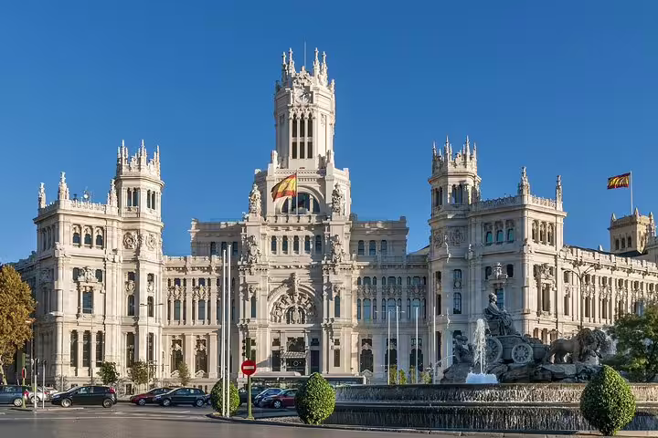 Palacio de Cibeles with Cibeles Fountain in Madrid, Spain, featuring Spanish flags and ornate white architecture