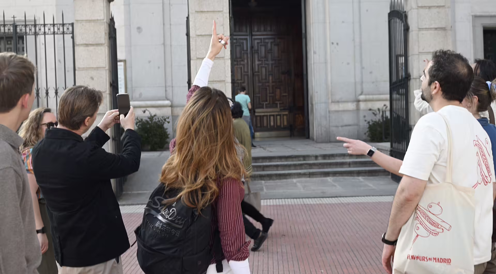 Tourists explore Madrid's rich culture on a guided tour, admiring historic architecture and capturing moments with smartphones.
