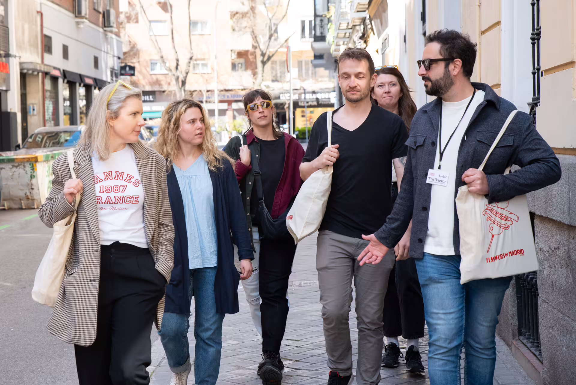 Group enjoying a guided walking tour in Madrid, exploring local cuisine, wine, and culture in vibrant city streets.