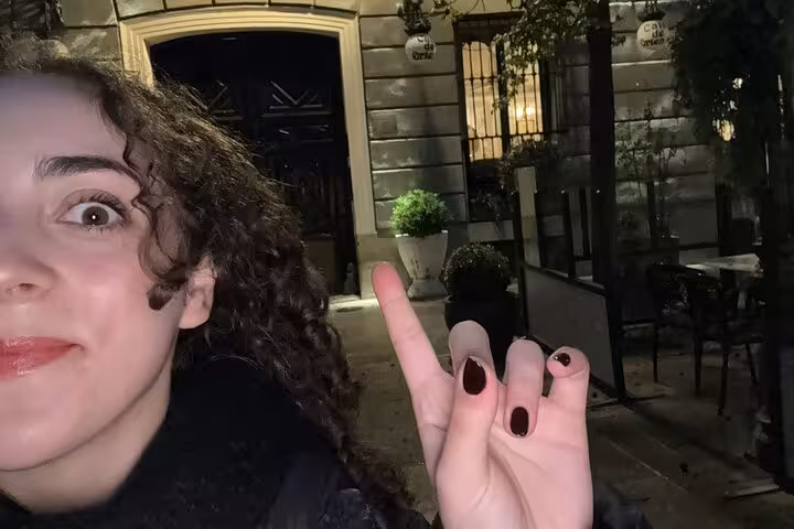 Woman making a spooky hand gesture on a dark Madrid street at night