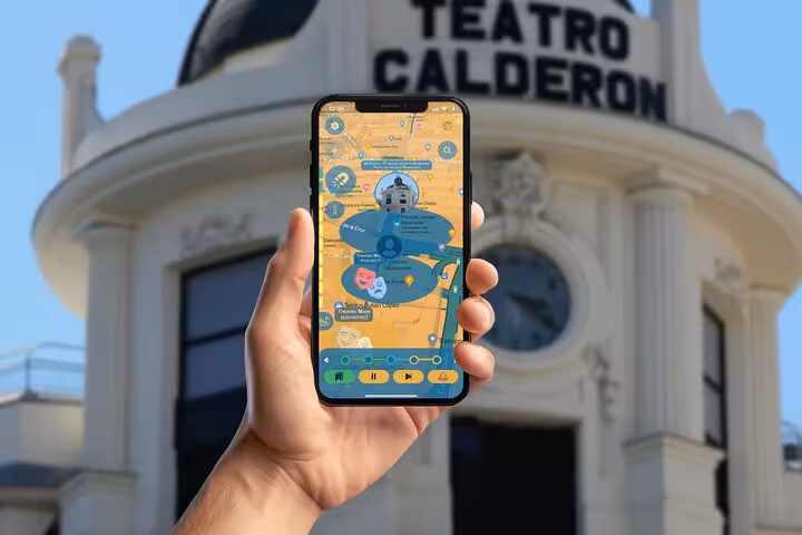 Self-guided walking tour app displayed on phone in front of historic Teatro Calderon in Madrid Spain