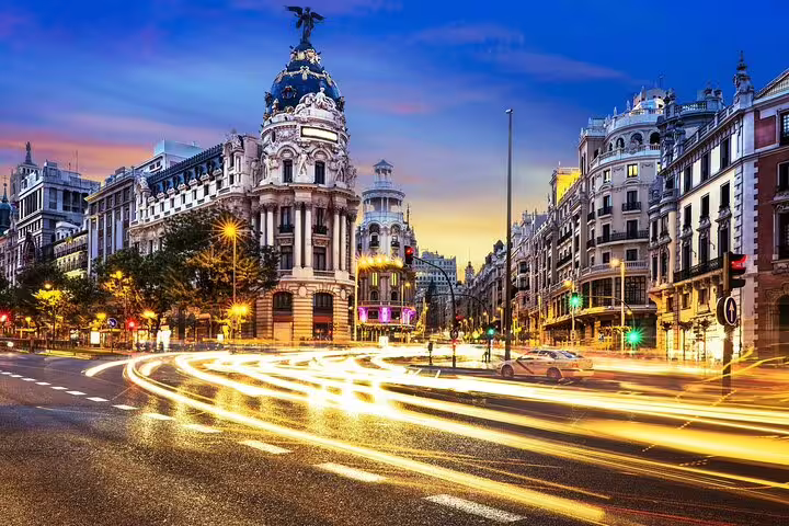 Madrid Gran Via intersection at dusk with light trails and ornate Metropolis building illuminated