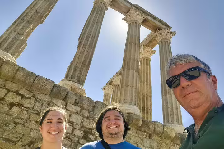 Travelers enjoy a sunny stop at the ancient Roman Temple of Évora during a private transfer from Madrid to Lisbon.
