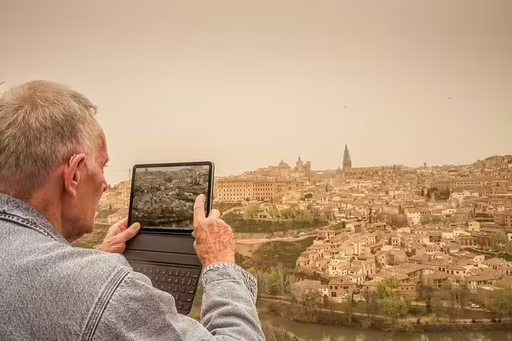 Senior traveler capturing the historic cityscape of Toledo on a digital device during a scenic Madrid to Lisbon private transfer.