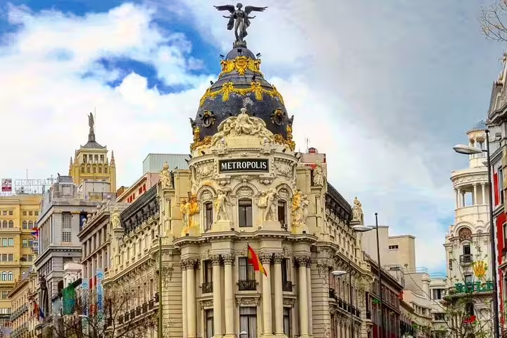 Metropolis Building ornate facade with golden dome and angel statue on Madrid city tour