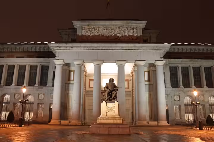 Prado Museum illuminated at night with Velázquez statue in Madrid