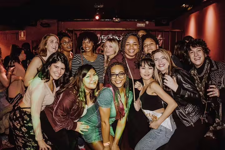 Smiling group of diverse friends at a lively bar during the Madrid pub crawl, showcasing the tour's social vibe.