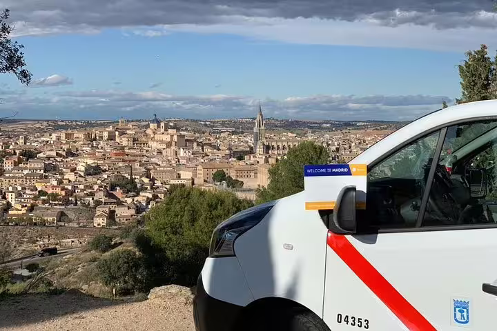 Private day trip from Madrid to Toledo with chauffeured van parked at scenic city viewpoint overlook