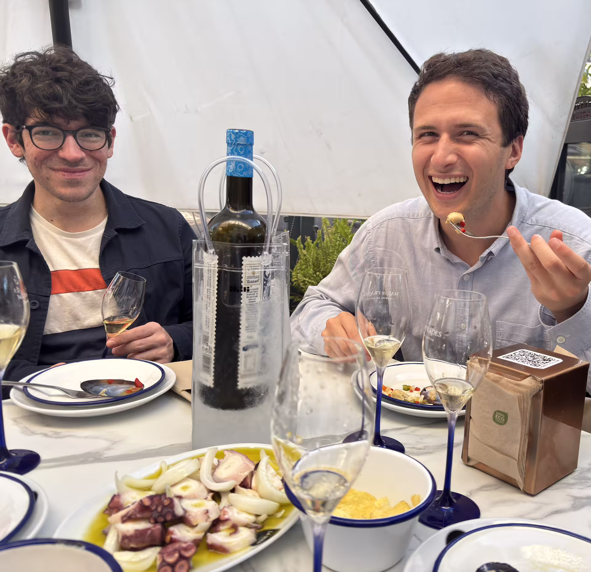 Two people enjoying wine and traditional Spanish cuisine at an outdoor table during an Authentic Madrid Food, Wine, and Culture Tour.