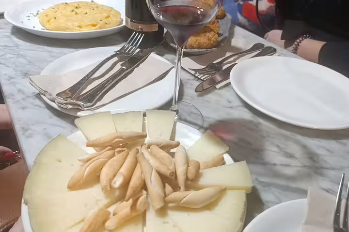 Spanish cheese platter with breadsticks and red wine on Madrid City Wine Tour.